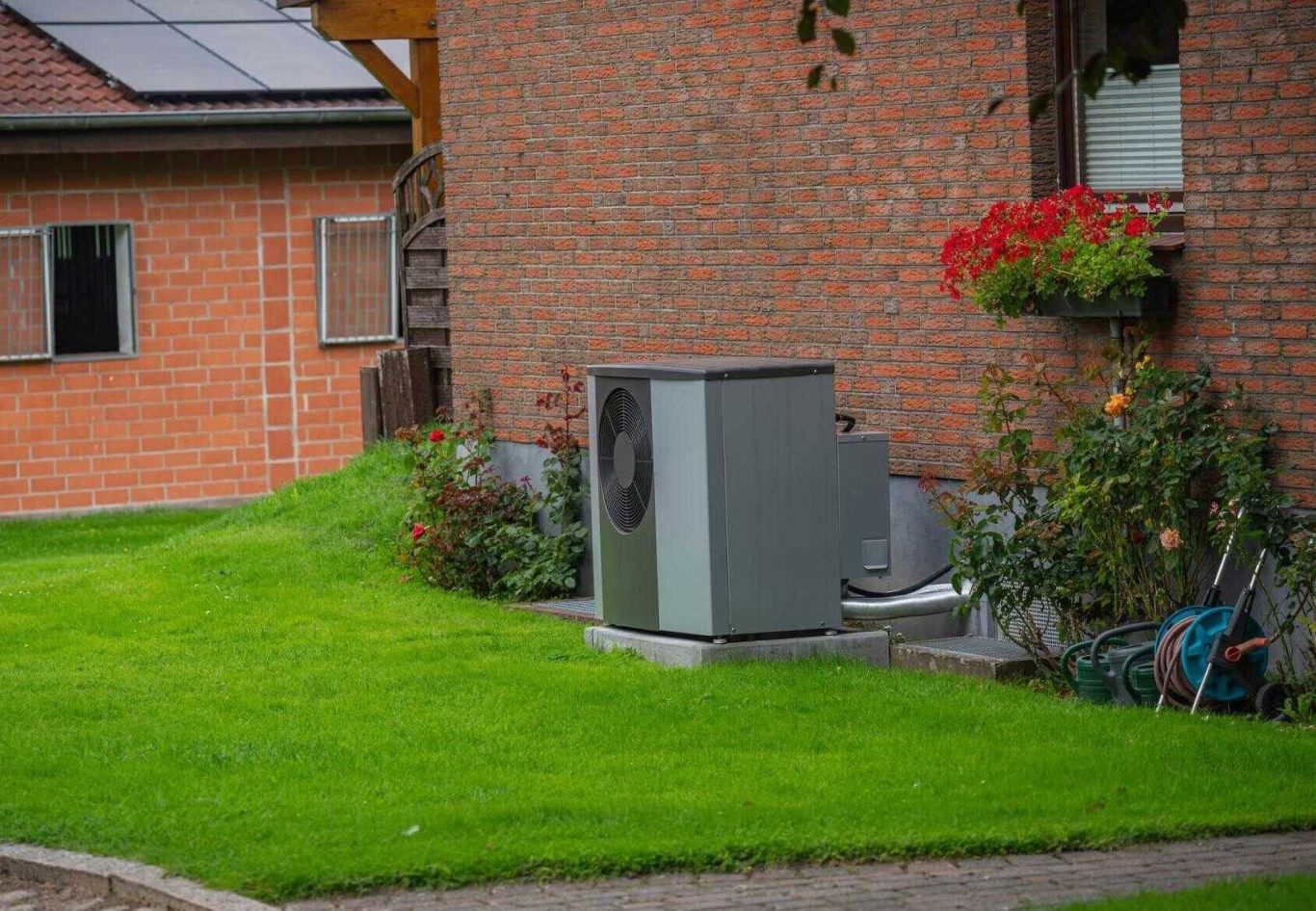 Luftwärmepumpe Außeneinheit an der Hauswand im Vorgarten auf dem Land.