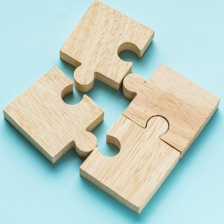 Holzene Puzzle-Teile, die ineinandergreifen, als Symbol für aufeinander abgestimmte Photovoltaik- und Wärmepumpenkonzepte.